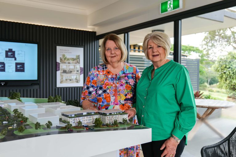 Friends Cheryl and Denise standing next to a model of Fairway Carindale.