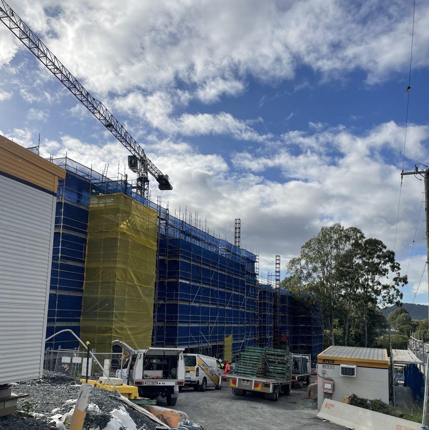 Construction site at Fairway Carindale with crane behind a blue scaffolding and ute in front of building.