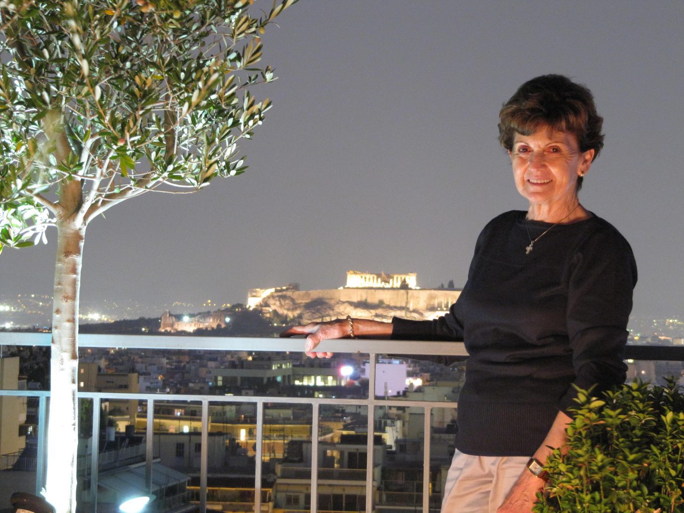 Future Fairway resident Helen Panaretos standing on a lit balcony with an olive tree next to her.