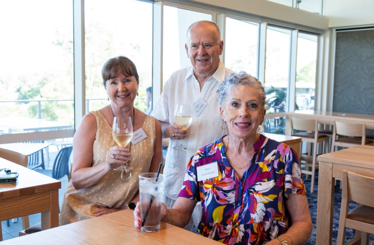Three residents, smiling and holding drinks to celebrate the launch of Fairway Carindale.
